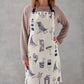 Kitchen apron featuring repeating design of navy nautical icons, Women's nautical apron featuring repeating navy design with beach chairs and sailboats, Men's nautical apron featuring repeating beach design in navy