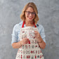 Adult's Christmas apron featuring various London Christmas icons, Red strapped London icons Christmas apron, Hand illustrated Christmas apron, Cotton Christmas apron featuring iconic London Christmas favorites, Christmas apron with repeating London Christ