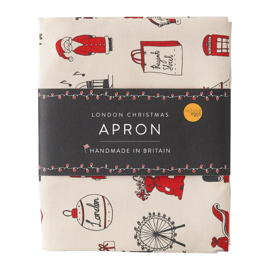 Adult's Christmas apron featuring various London Christmas icons, Red strapped London icons Christmas apron, Hand illustrated Christmas apron, Cotton Christmas apron featuring iconic London Christmas favorites, Christmas apron with repeating London Christ
