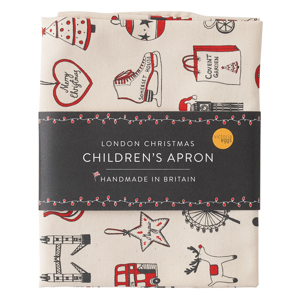 Children's London Christmas apron featuring repeating London landmarks, Kids kitchen apron featuring iconic London Christmas icons, Children's Christmas kitchen apron with red strap, Cotton Children's Christmas apron featuring ice skates and The London Ey