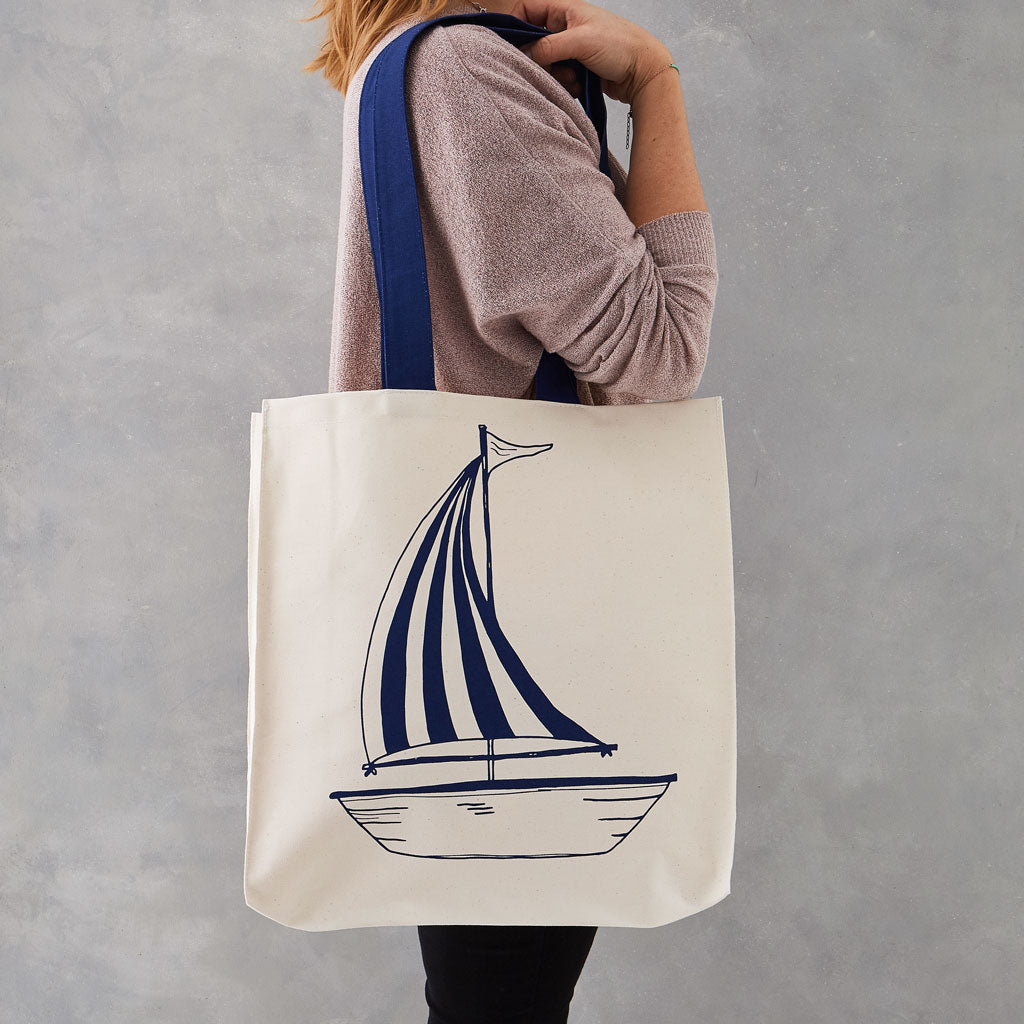 Double sided canvas bag featuring nautical design of an anchor and sailboat, Nautical canvas bag featuring both an anchor and sailboat design in navy, Reusable nautical bag featuring large anchor and sailboat design in navy